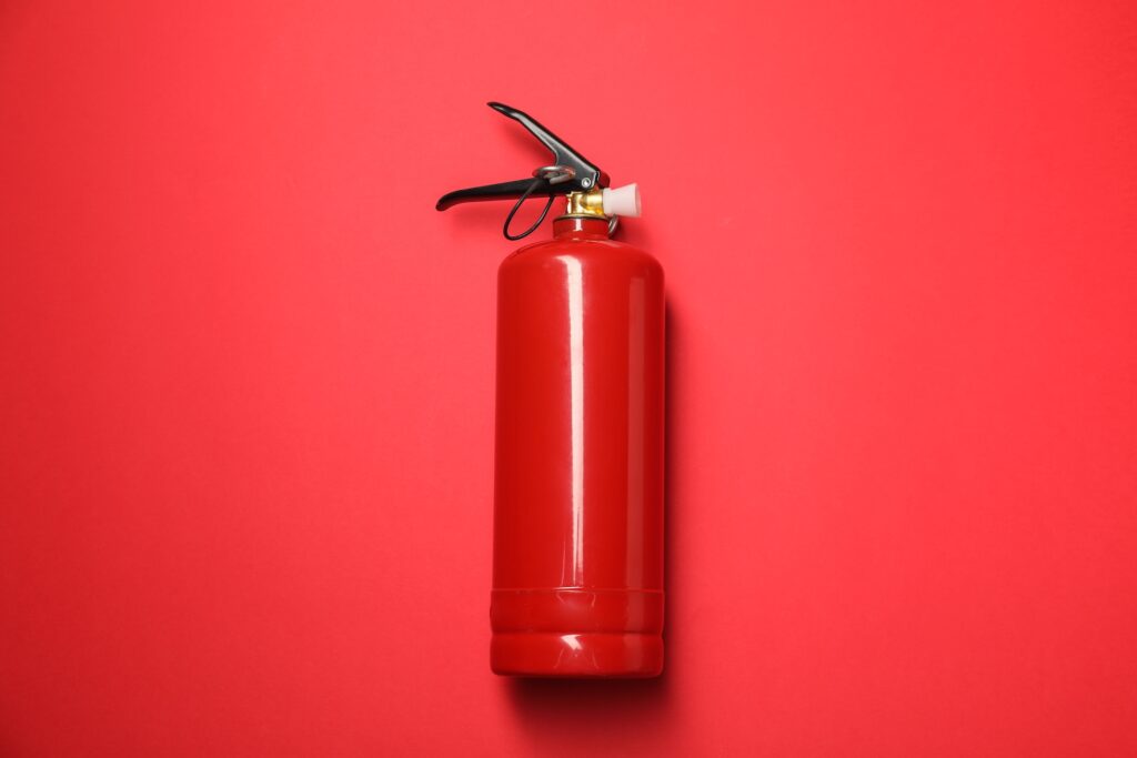 Extintor rojo sobre fondo rojo, metáfora de la necesidad de que el empresario deje de apagar fuegos operativos diarios.