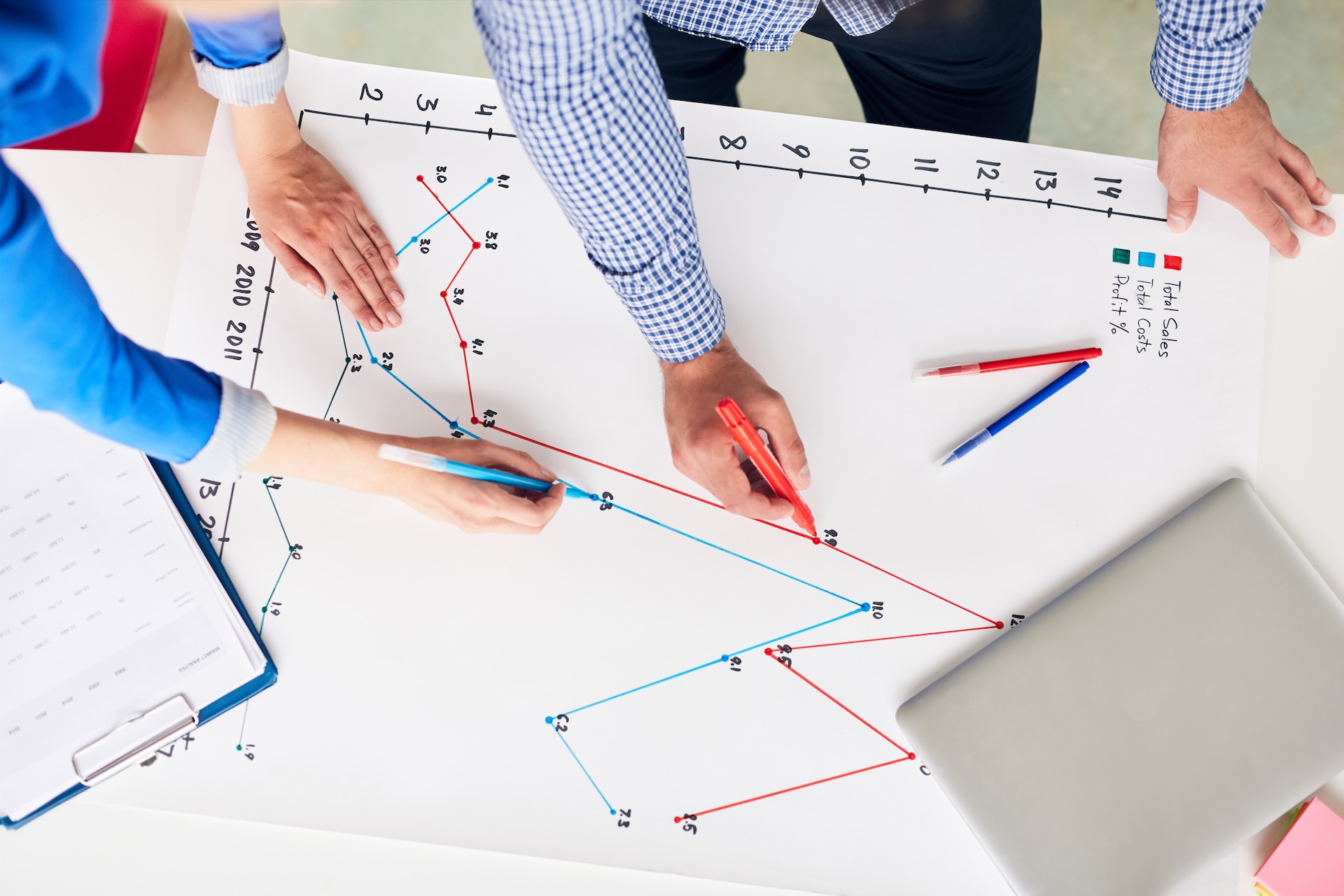 Mentor y gerente analizando conjuntamente un gráfico de rendimiento empresarial con líneas azul y roja.