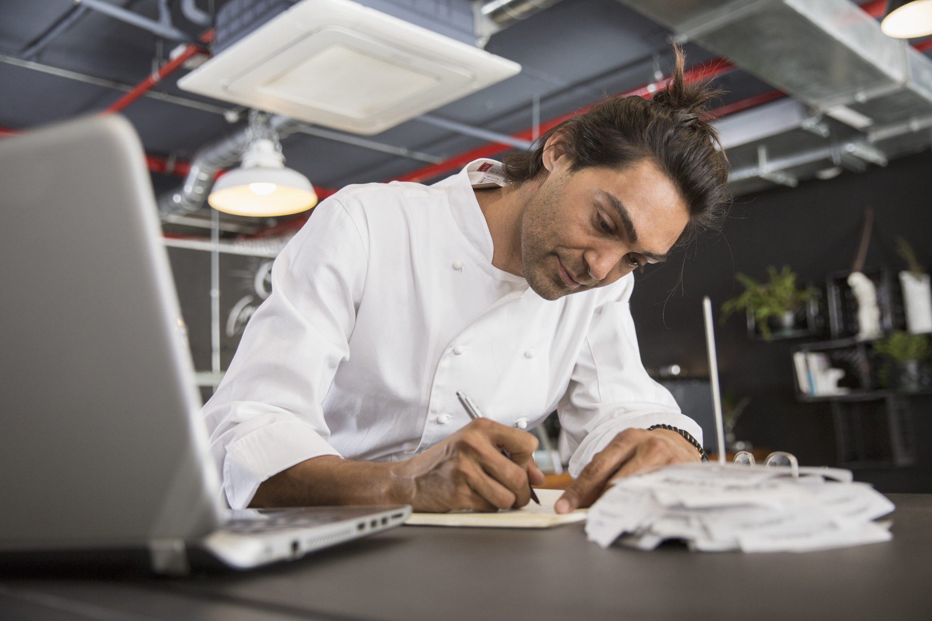 Dueño de negocio de hostelería o catering revisando costes y rentabilidad frente al portátil.