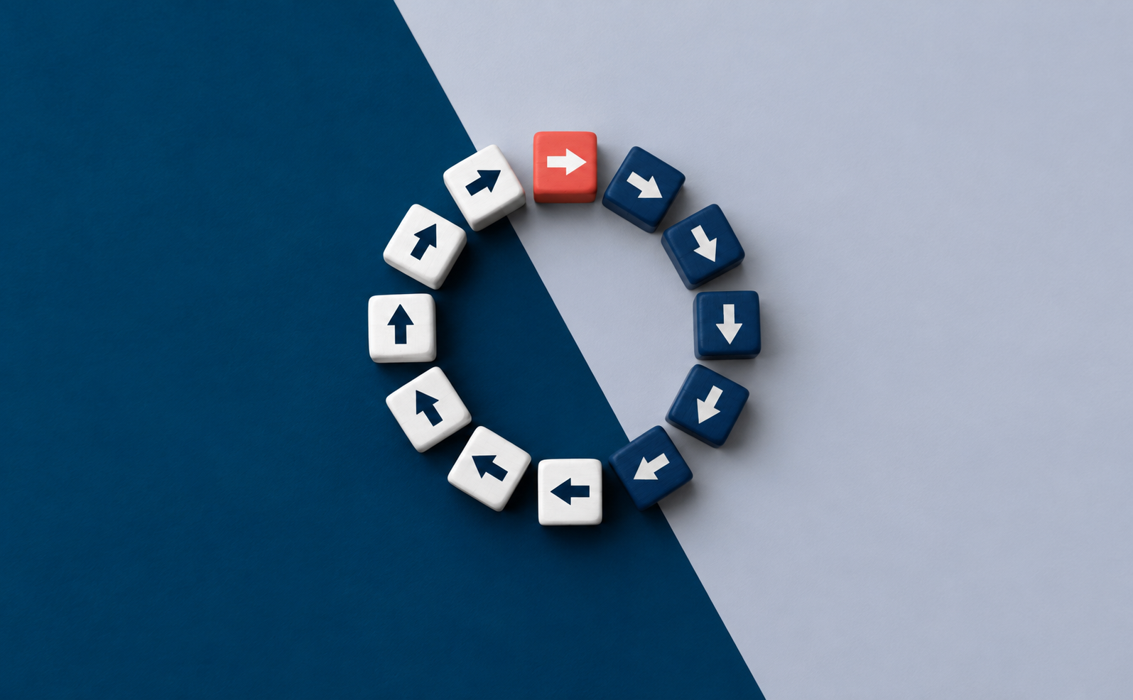 Cubos con flechas formando un círculo sobre fondo azul y gris, con un cubo rojo que marca el inicio del ciclo de seguimiento de un modelo de coaching empresarial.
